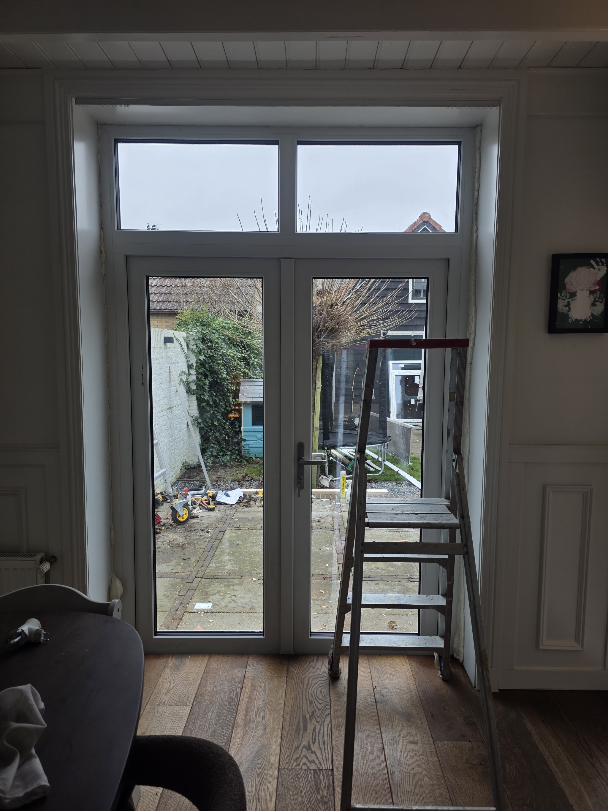 Nieuwe witte openslaande tuindeuren met bovenlicht, gezien van binnen
