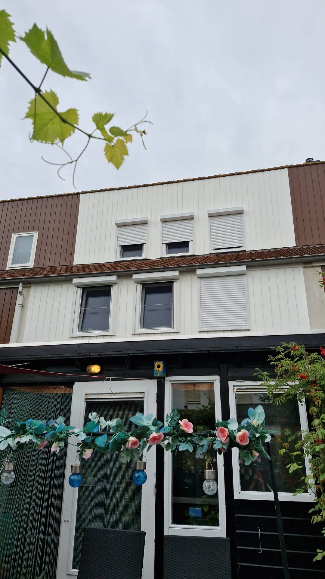 Rijwoning met nieuwe witte gevelbekleding, kozijnen en rolluiken op de verdieping